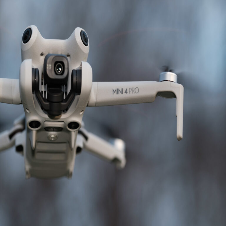 A close-up view of a Mini 4 Pro drone showing its camera and one arm.